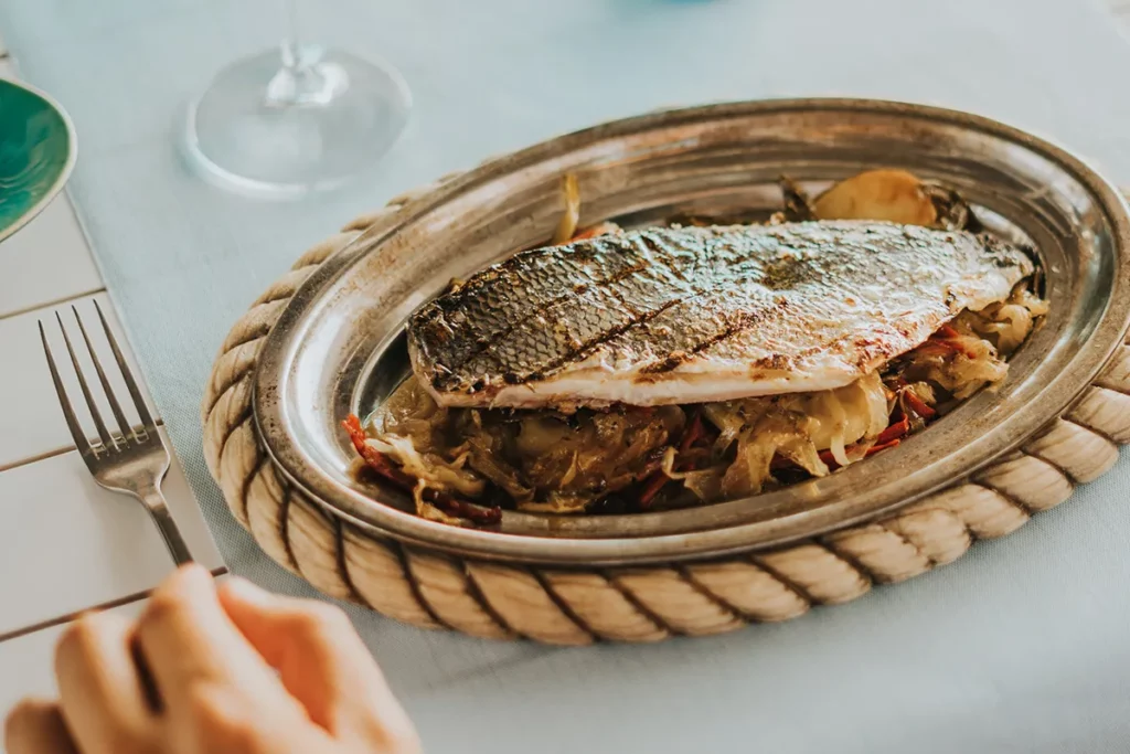 Dorada a la brasa a la bilbaína con papas panaderas servida en fuente de metal