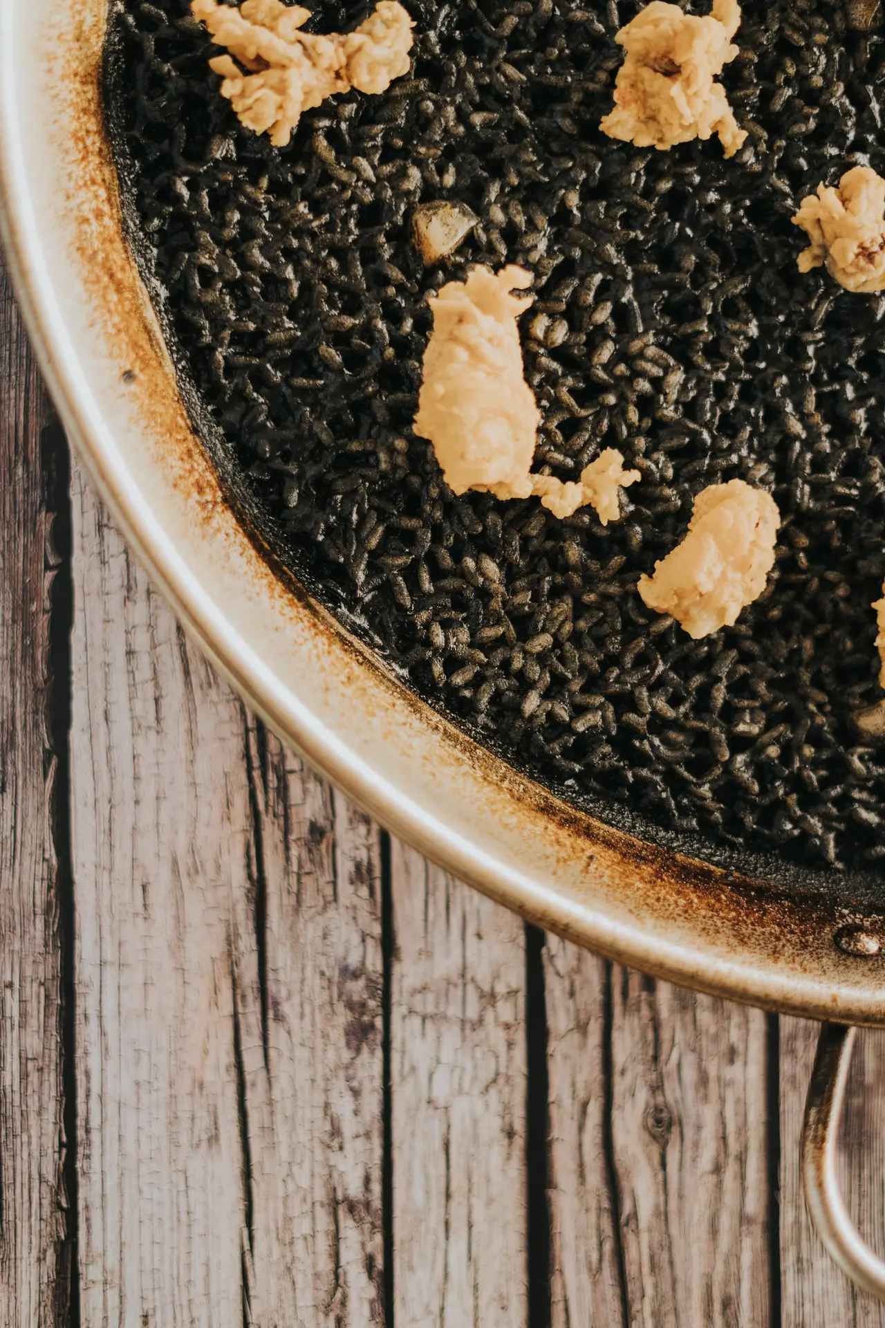 Socarrat en el borde de la paellera de arroz negro en Bésame Mucho, Costa Adeje, Tenerife