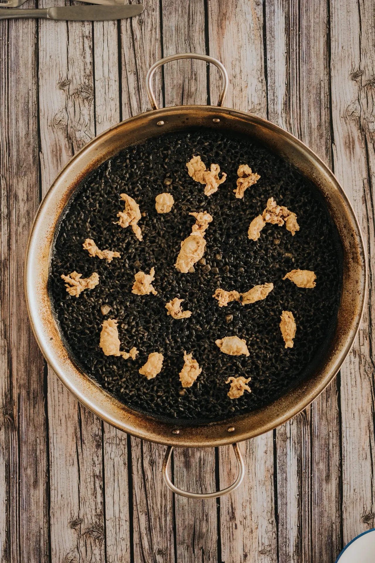 Arroz negro de sepia con chopitos fritos en paellera, vista cenital, en Bésame Mucho, Costa Adeje, Tenerife